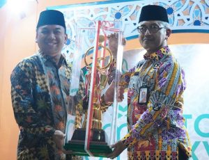 Uus Kuswanto saat menyerahkan piala Juara Umum kepada Walikota Jakbar, Yani Wahyu Perwoko.